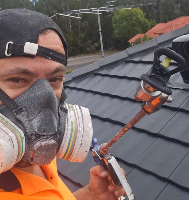 Klean Kingdom owner spray painting a concrete tile roof with respirator and full PPE during a roof restoration job in Mount Annan, Sydney